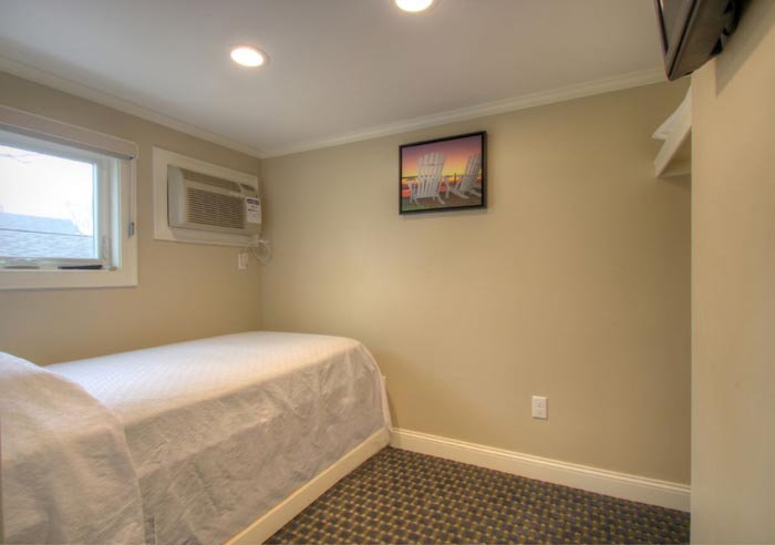 Twin and trundle beds with flat screen TV in back room.