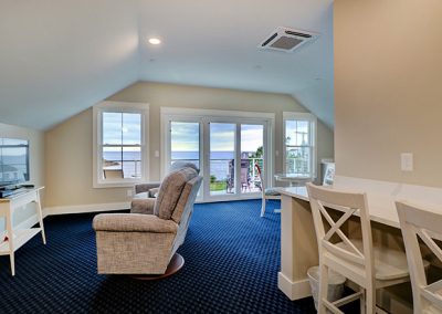 View from entrance door, showing the TV and recliner area, the sliding door to the balcony and the desk.