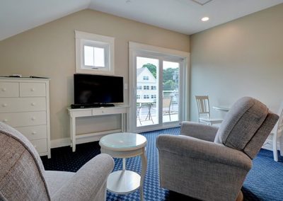 Seating area with two recliners and TV, dining area and balcony.