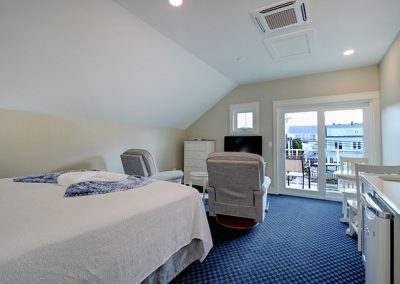 King bed, two recliners and TV, balcony, dining table and wet bar.