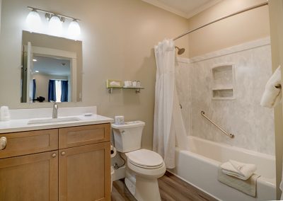 Room 72's bathroom with shower, tub and vanity. Curtain rod has been replaced with sliding shower doors.