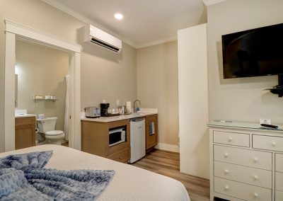 One of the two queen beds, bathroom entrance, wet bar, closet, bureau and TV.