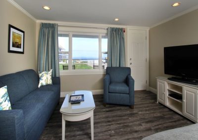 Queen sofa bed and seating area with TV and picture window facing the ocean.