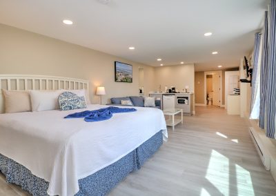 View from entrance of Room 40A, showing a king bed, sofa and wet bar. Alcove with trundle bed and door to bathroom beyond.