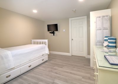 Alcove containing trundle bed and TV. Centered is door to the bathroom. Dresser and closet to the far right.
